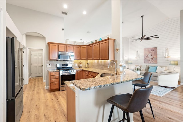 6750 64th Ter E, Bradenton, FL 34203 - kitchen featuring stainless steel appliances, high vaulted ceiling, a peninsula, a breakfast bar, and light wood finished floors
