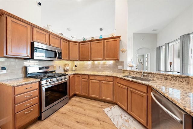 6750 64th Ter E, Bradenton, FL 34203 - kitchen with appliances with stainless steel finishes, light wood-type flooring, brown cabinetry, light stone countertops, and tasteful backsplash