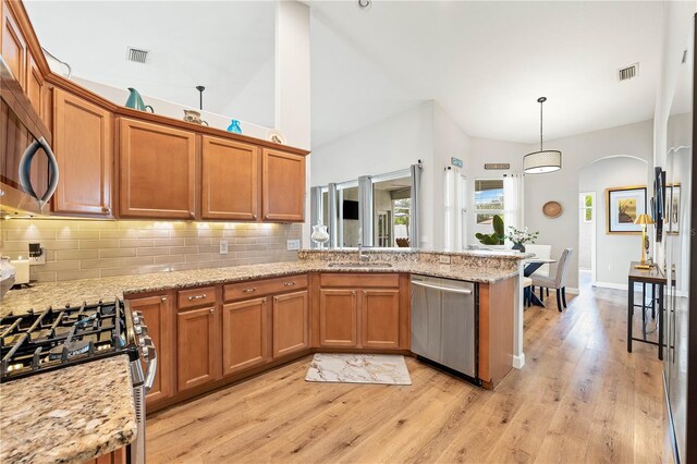 6750 64th Ter E, Bradenton, FL 34203 - kitchen featuring appliances with stainless steel finishes, brown cabinetry, a peninsula, and backsplash