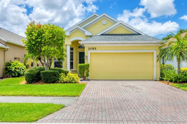 2085 Mattamy Ct, Venice, FL 34292 - ranch-style home with stucco siding, decorative driveway, an attached garage, and roof with shingles