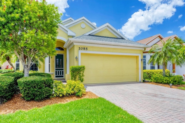 2085 Mattamy Ct, Venice, FL 34292 - view of front of house featuring stucco siding, a garage, decorative driveway, and roof with shingles