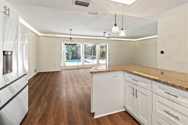 2515 Huntington Ave, Sarasota, FL 34232 - kitchen with stainless steel fridge, dark wood finished floors, light stone counters, white cabinets, and pendant lighting