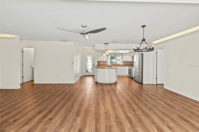 2515 Huntington Ave, Sarasota, FL 34232 - unfurnished living room with a chandelier, baseboards, light wood-style flooring, and ceiling fan