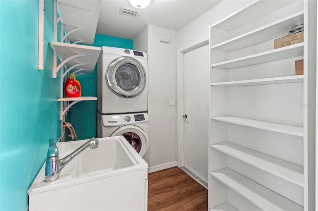 2515 Huntington Ave, Sarasota, FL 34232 - laundry area featuring stacked washing machine and dryer, dark wood-type flooring, a textured ceiling, and baseboards