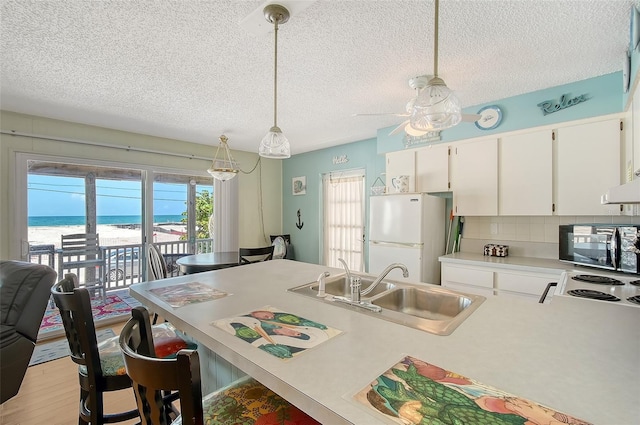 1103 Shore View Dr, Englewood, FL 34223 - kitchen featuring freestanding refrigerator, a sink, light countertops, black microwave, and view of water and beach