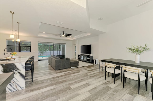 2546 Malibu Ln, North Port, FL 34286 - living room with a raised ceiling, light wood-style flooring, a ceiling fan, and a chandelier