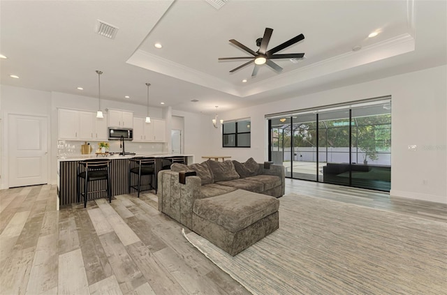 2546 Malibu Ln, North Port, FL 34286 - living area with a tray ceiling, recessed lighting, ceiling fan, light wood-style flooring, and crown molding