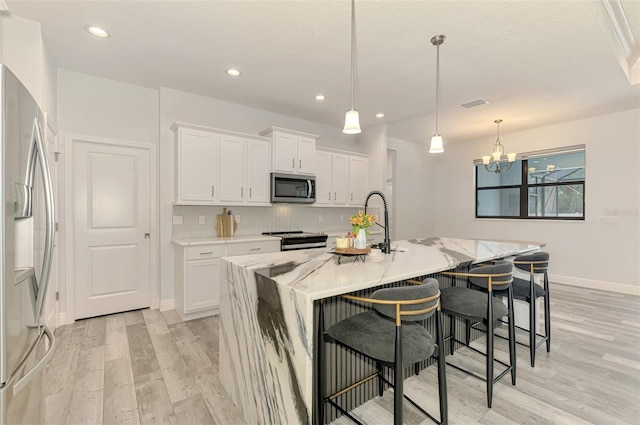 2546 Malibu Ln, North Port, FL 34286 - kitchen featuring stainless steel appliances, light wood-type flooring, white cabinetry, a breakfast bar, and light stone countertops