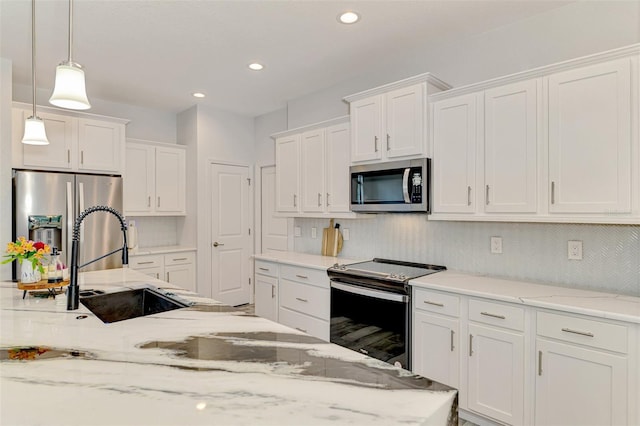 2546 Malibu Ln, North Port, FL 34286 - kitchen featuring appliances with stainless steel finishes, a sink, white cabinetry, hanging light fixtures, and backsplash