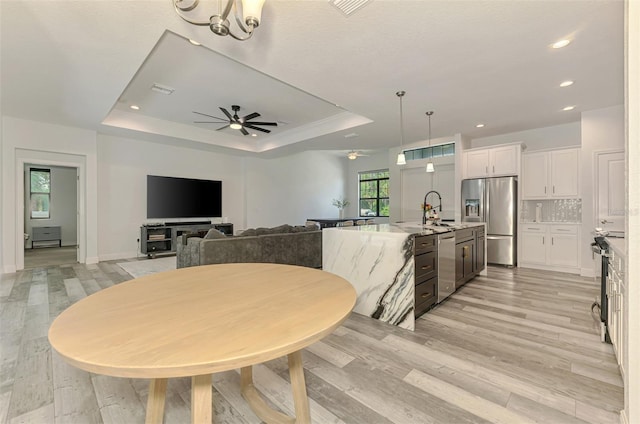 2546 Malibu Ln, North Port, FL 34286 - dining space featuring a tray ceiling, ceiling fan, light wood-style floors, baseboards, and recessed lighting