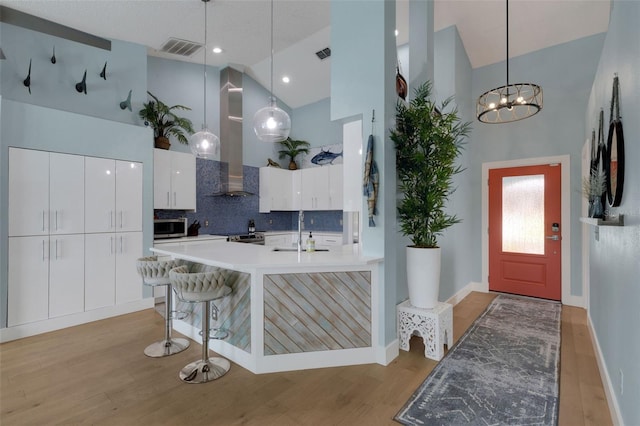 4120 51st Dr W, Bradenton, FL 34210 - kitchen with high vaulted ceiling, stainless steel microwave, light wood-style flooring, white cabinets, and tasteful backsplash