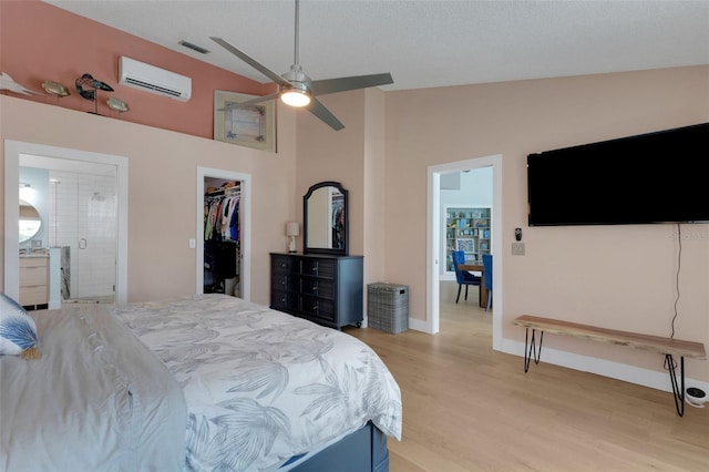 4120 51st Dr W, Bradenton, FL 34210 - bedroom featuring a wall mounted AC, light wood-type flooring, a walk in closet, ensuite bathroom, and high vaulted ceiling