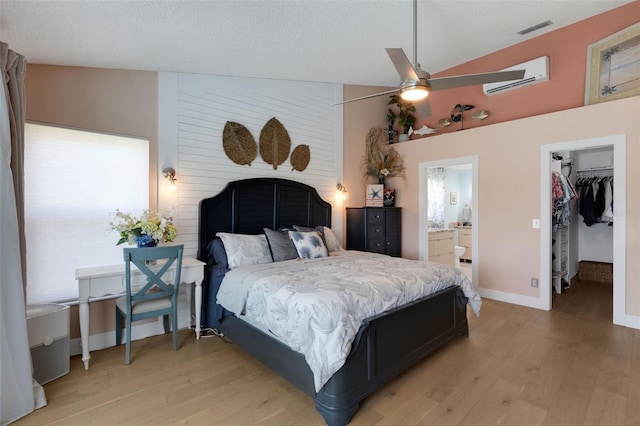4120 51st Dr W, Bradenton, FL 34210 - bedroom featuring a wall unit AC, light wood-style floors, a spacious closet, ensuite bathroom, and high vaulted ceiling