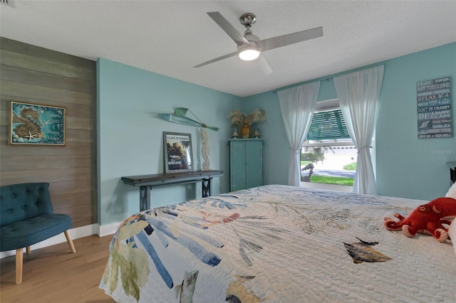4120 51st Dr W, Bradenton, FL 34210 - bedroom with wood finished floors, wood walls, a textured ceiling, and ceiling fan