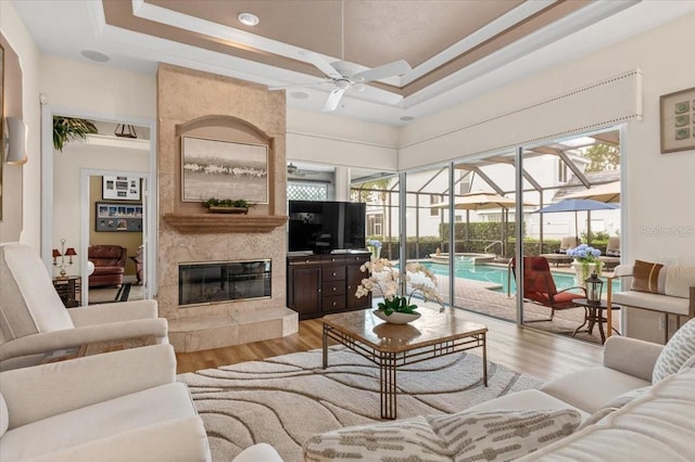 7513 Coventry Ct, Lakewood Ranch, FL 34202 - living room featuring ceiling fan, a sunroom, a raised ceiling, light wood finished floors, and healthy amount of natural light