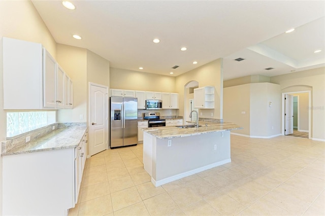 8772 Stone Harbour Loop, Bradenton, FL 34212 - kitchen featuring appliances with stainless steel finishes, arched walkways, white cabinets, light tile patterned floors, and light stone countertops