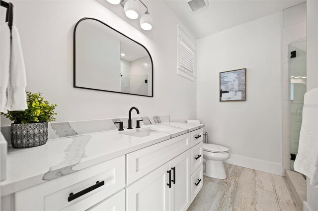 109 Palmetto Ave, Anna Maria, FL 34216 - bathroom with vanity, wood finished floors, toilet, tiled shower, and baseboards