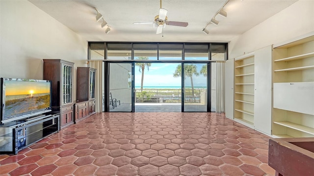 222 Beach Rd Unit 7, Sarasota, FL 34242 - unfurnished living room with rail lighting, a wall of windows, built in shelves, and ceiling fan