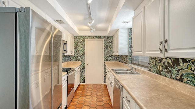 222 Beach Rd Unit 7, Sarasota, FL 34242 - kitchen with appliances with stainless steel finishes, wallpapered walls, track lighting, white cabinets, and light countertops