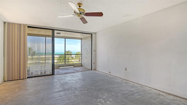 222 Beach Rd Unit 7, Sarasota, FL 34242 - empty room featuring expansive windows, unfinished concrete flooring, a ceiling fan, a textured ceiling, and a water view
