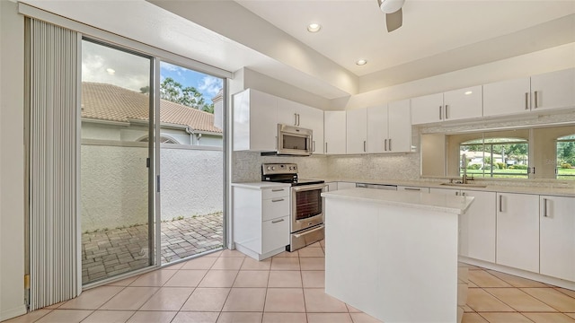 3317 Highlands Bridge Rd Unit 61, Sarasota, FL 34235 - kitchen with appliances with stainless steel finishes, light countertops, light tile patterned floors, a center island, and white cabinetry