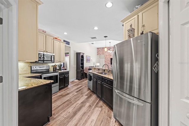 743 Stonecrest Dr, Sarasota, FL 34232 - kitchen with stainless steel appliances, cream cabinetry, a sink, light wood-type flooring, and tasteful backsplash