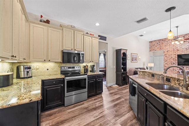 743 Stonecrest Dr, Sarasota, FL 34232 - kitchen with stainless steel appliances, cream cabinetry, a sink, dark cabinets, and recessed lighting