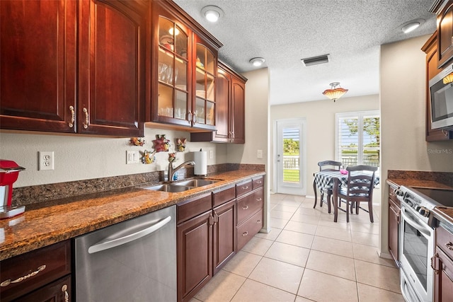 4194 Banbury Cir, Parrish, FL 34219 - kitchen with stainless steel appliances, a sink, glass insert cabinets, light tile patterned floors, and a textured ceiling