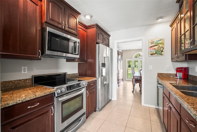 4194 Banbury Cir, Parrish, FL 34219 - kitchen with appliances with stainless steel finishes, glass insert cabinets, light tile patterned flooring, baseboards, and a textured ceiling