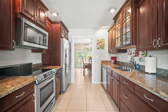 4194 Banbury Cir, Parrish, FL 34219 - kitchen featuring stainless steel appliances, a sink, glass insert cabinets, light tile patterned flooring, and dark stone countertops