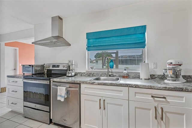 107 Van Dyck Dr, Nokomis, FL 34275 - kitchen with appliances with stainless steel finishes, wall chimney exhaust hood, a sink, white cabinetry, and light tile patterned floors