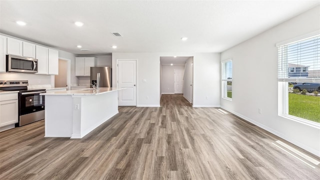12064 Lansing Gln, Parrish, FL 34219 - kitchen with stainless steel appliances, light wood-style floors, a kitchen island with sink, light countertops, and recessed lighting