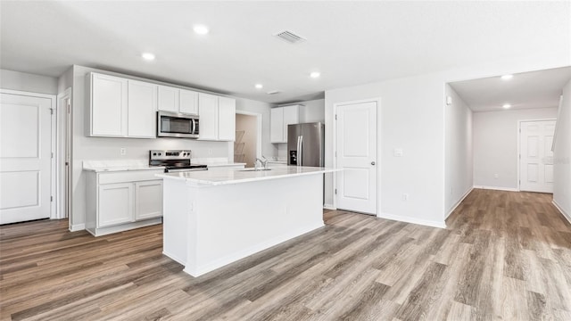 12064 Lansing Gln, Parrish, FL 34219 - kitchen with appliances with stainless steel finishes, light wood-style floors, an island with sink, white cabinetry, and recessed lighting