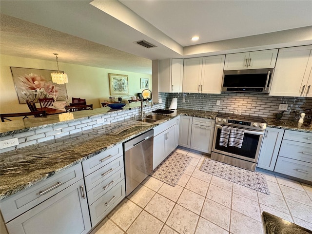 3500 El Conquistador Pkwy Unit 347, Bradenton, FL 34210 - kitchen with appliances with stainless steel finishes, decorative backsplash, dark stone counters, hanging light fixtures, and recessed lighting