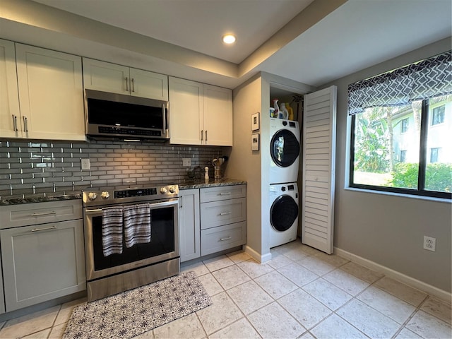 3500 El Conquistador Pkwy Unit 347, Bradenton, FL 34210 - kitchen with appliances with stainless steel finishes, stacked washer / drying machine, backsplash, dark stone countertops, and light tile patterned floors
