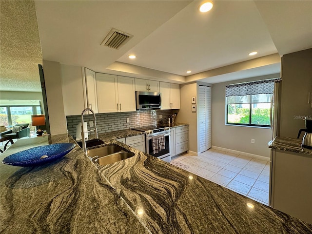 3500 El Conquistador Pkwy Unit 347, Bradenton, FL 34210 - kitchen featuring stainless steel appliances, light tile patterned flooring, white cabinets, backsplash, and dark stone counters