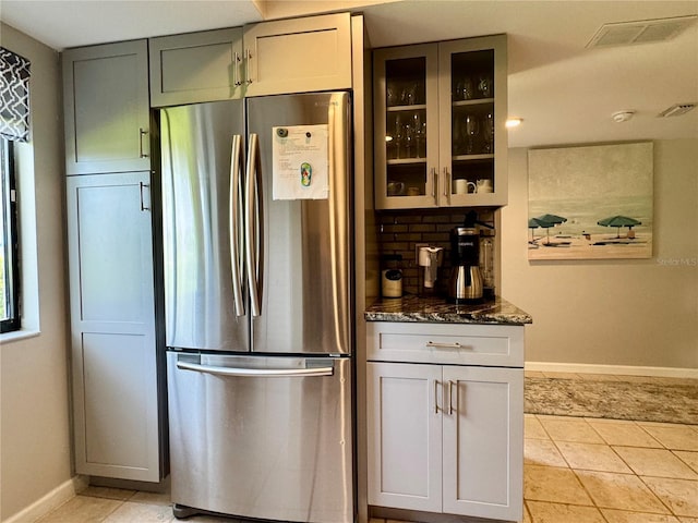 3500 El Conquistador Pkwy Unit 347, Bradenton, FL 34210 - kitchen featuring freestanding refrigerator, glass insert cabinets, dark stone counters, light tile patterned floors, and decorative backsplash