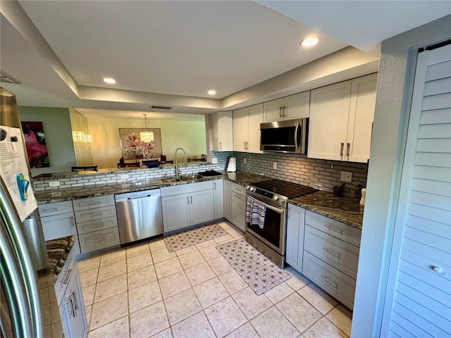 3500 El Conquistador Pkwy Unit 347, Bradenton, FL 34210 - kitchen featuring appliances with stainless steel finishes, a tray ceiling, tasteful backsplash, dark stone counters, and recessed lighting