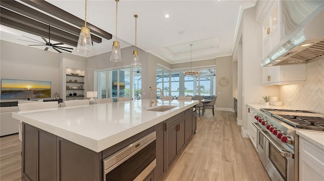 8537 Pavia Way, Bradenton, FL 34202 - kitchen with wall chimney exhaust hood, appliances with stainless steel finishes, decorative backsplash, light wood-style flooring, and white cabinets
