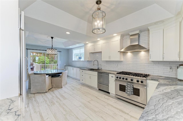 8963 Fishermens Bay Dr, Sarasota, FL 34231 - kitchen with wall chimney exhaust hood, appliances with stainless steel finishes, white cabinets, tasteful backsplash, and a chandelier