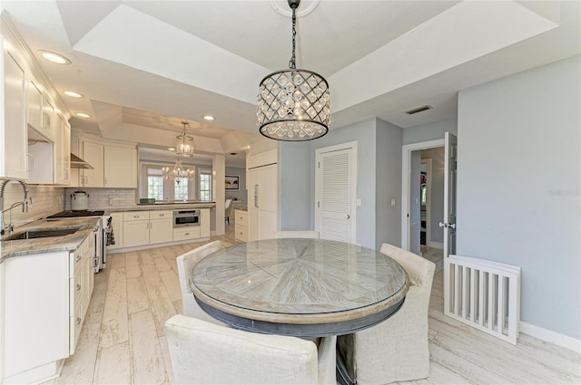 8963 Fishermens Bay Dr, Sarasota, FL 34231 - dining room with a chandelier, a raised ceiling, recessed lighting, and light wood-style flooring