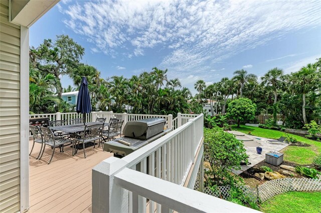8963 Fishermens Bay Dr, Sarasota, FL 34231 - deck with outdoor dining area, view of wooded area, and a grill