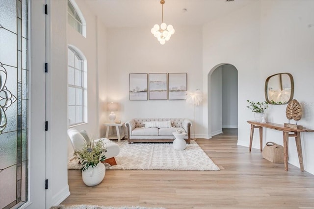 800 NW 36th Ave, Cape Coral, FL 33993 - living room featuring arched walkways, a high ceiling, wood finished floors, a chandelier, and baseboards