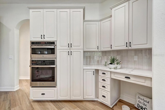 800 NW 36th Ave, Cape Coral, FL 33993 - kitchen with stainless steel double oven, arched walkways, light wood-type flooring, light stone countertops, and backsplash