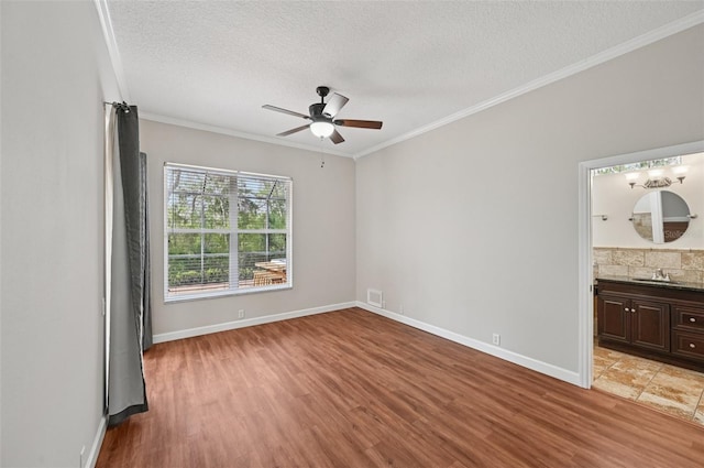6744 Hickory Hammock Cir, Bradenton, FL 34202 - empty room with a sink, a textured ceiling, ceiling fan, light wood-style flooring, and ornamental molding