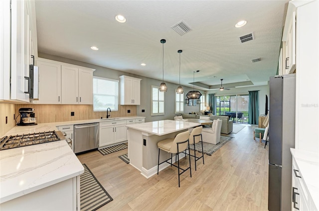 17898 Cherished Loop, Bradenton, FL 34211 - kitchen with stainless steel appliances, open floor plan, a sink, light wood-style floors, and a kitchen bar