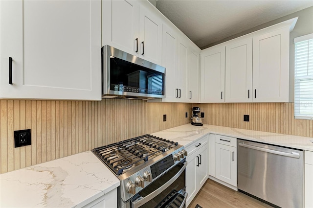 17898 Cherished Loop, Bradenton, FL 34211 - kitchen with stainless steel appliances, white cabinetry, light stone countertops, and light wood-type flooring