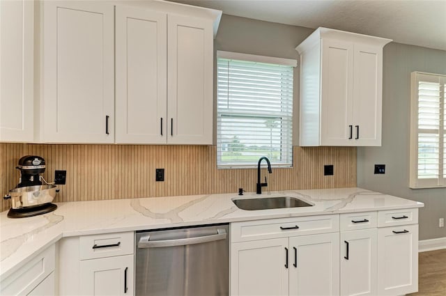 17898 Cherished Loop, Bradenton, FL 34211 - kitchen with stainless steel dishwasher, a sink, white cabinets, light stone countertops, and wood walls
