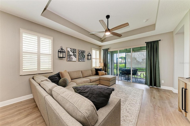 17898 Cherished Loop, Bradenton, FL 34211 - living room featuring a tray ceiling, ceiling fan, baseboards, and light wood-type flooring