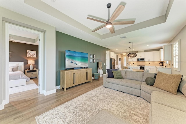 17898 Cherished Loop, Bradenton, FL 34211 - living room featuring light wood-style flooring, ceiling fan, baseboards, recessed lighting, and a raised ceiling
